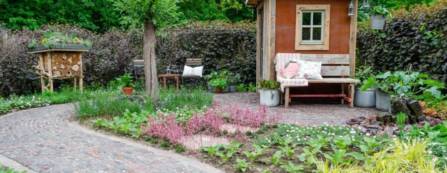Grünes Refugium, Insektenhotel, Gartenhütte, gepflasterter Weg und Pflanzen